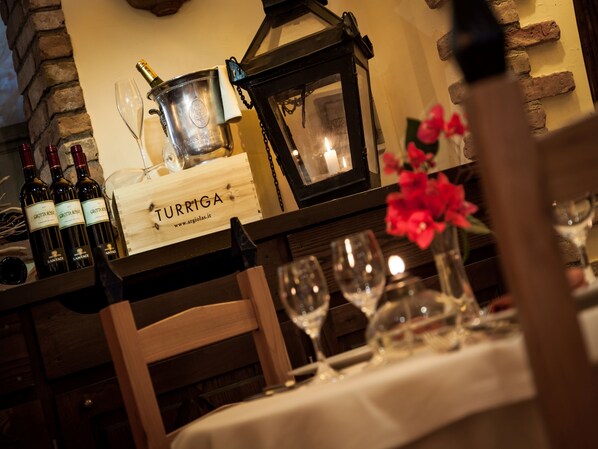 Un ambiente de restaurante con una mesa lista para comer, una alacena para vinos con botellas y un letrero que dice "TURRIGA".