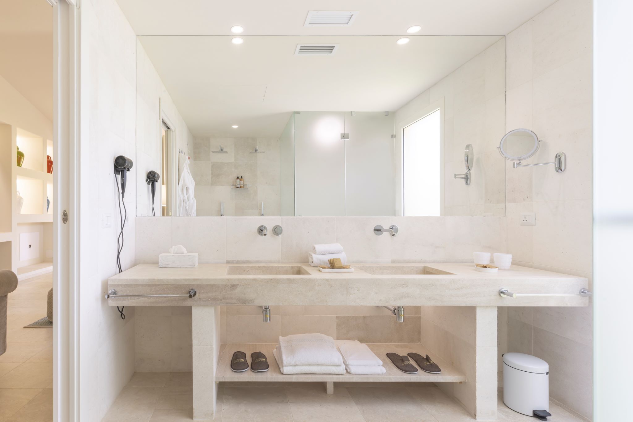 Une salle de bain moderne avec un grand miroir, deux lavabos et un meuble-lavabo doté d’un porte-serviettes.