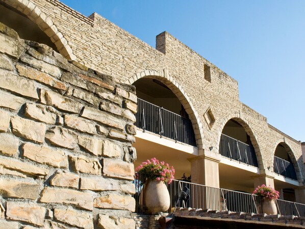 A stone building with arched balconies and large flower pots. - Hotel Costa Dei Fiori (Pula)