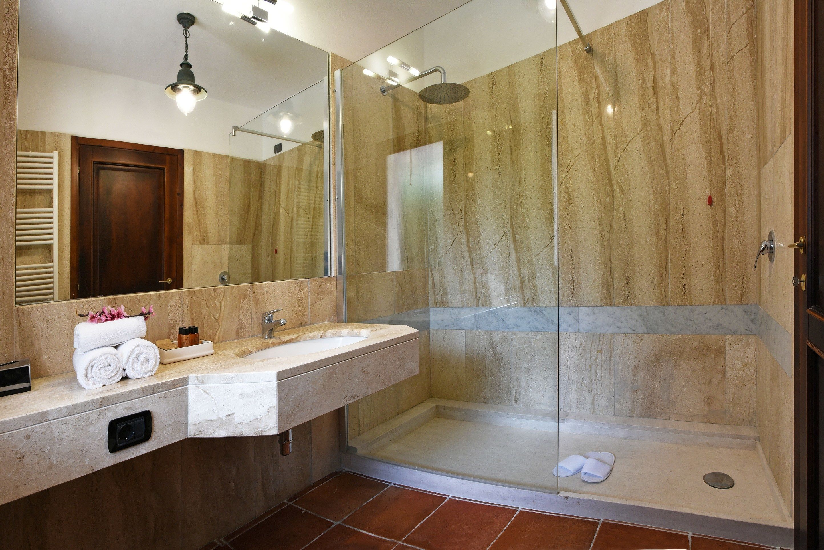 A modern bathroom with a marble vanity, a glass-enclosed shower, and a large mirror.