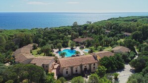 A coastal resort with a central swimming pool, surrounded by lush greenery and terracotta-roofed villas. - Hotel Costa Dei Fiori (Pula)