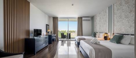 A modern hotel room with a large bed, a desk with a TV, and a view of the outdoors.