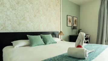 Una habitación de hotel con una cama grande, un cabecero, una mesita de noche, una lámpara, una silla y una ventana con cortinas.