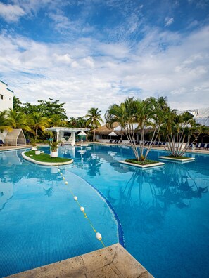 A swimming pool with clear blue water, surrounded by palm trees and lounge chairs. - Playa Blanca Beach Resort - All Inclusive (Rio Hato)