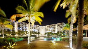 A hotel with a central courtyard, palm trees, and a wooden deck. - Playa Blanca Beach Resort - All Inclusive (Rio Hato)
