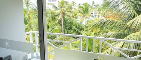 Un balcón con vista a palmeras y suelo de baldosas.