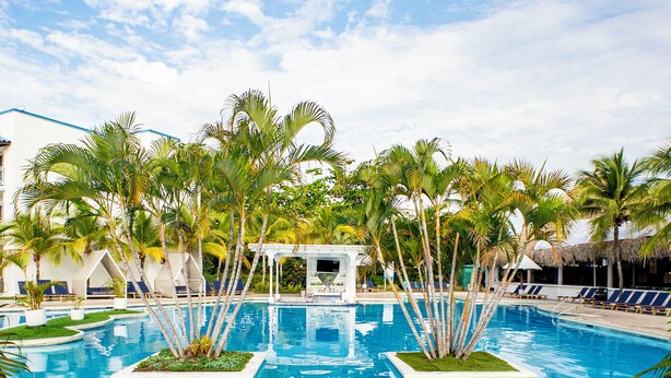 A swimming pool with palm trees, lounge chairs, and a gazebo. - Playa Blanca Beach Resort - All Inclusive (Rio Hato)