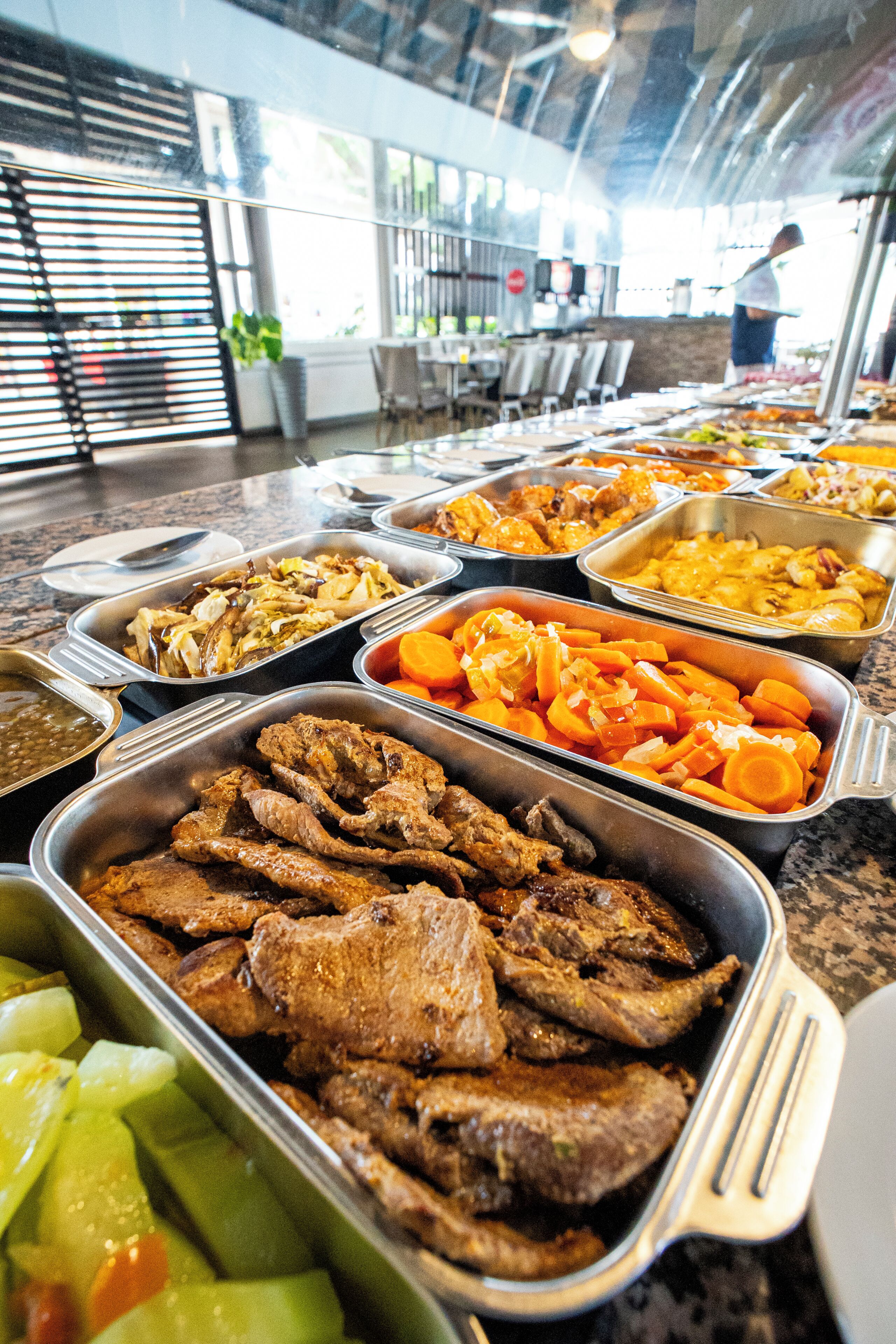 Un bufé con diversas opciones de comida, incluyendo carnes, verduras y ensaladas.
