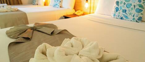 A hotel room with a neatly made bed, a bedside table with a towel, and a wooden headboard.
