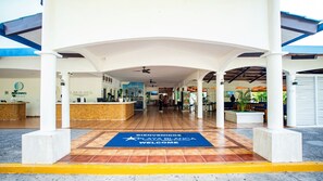A hotel reception area with a reception desk, a blue welcome mat, and a tiled floor. - Playa Blanca Beach Resort - All Inclusive (Rio Hato)