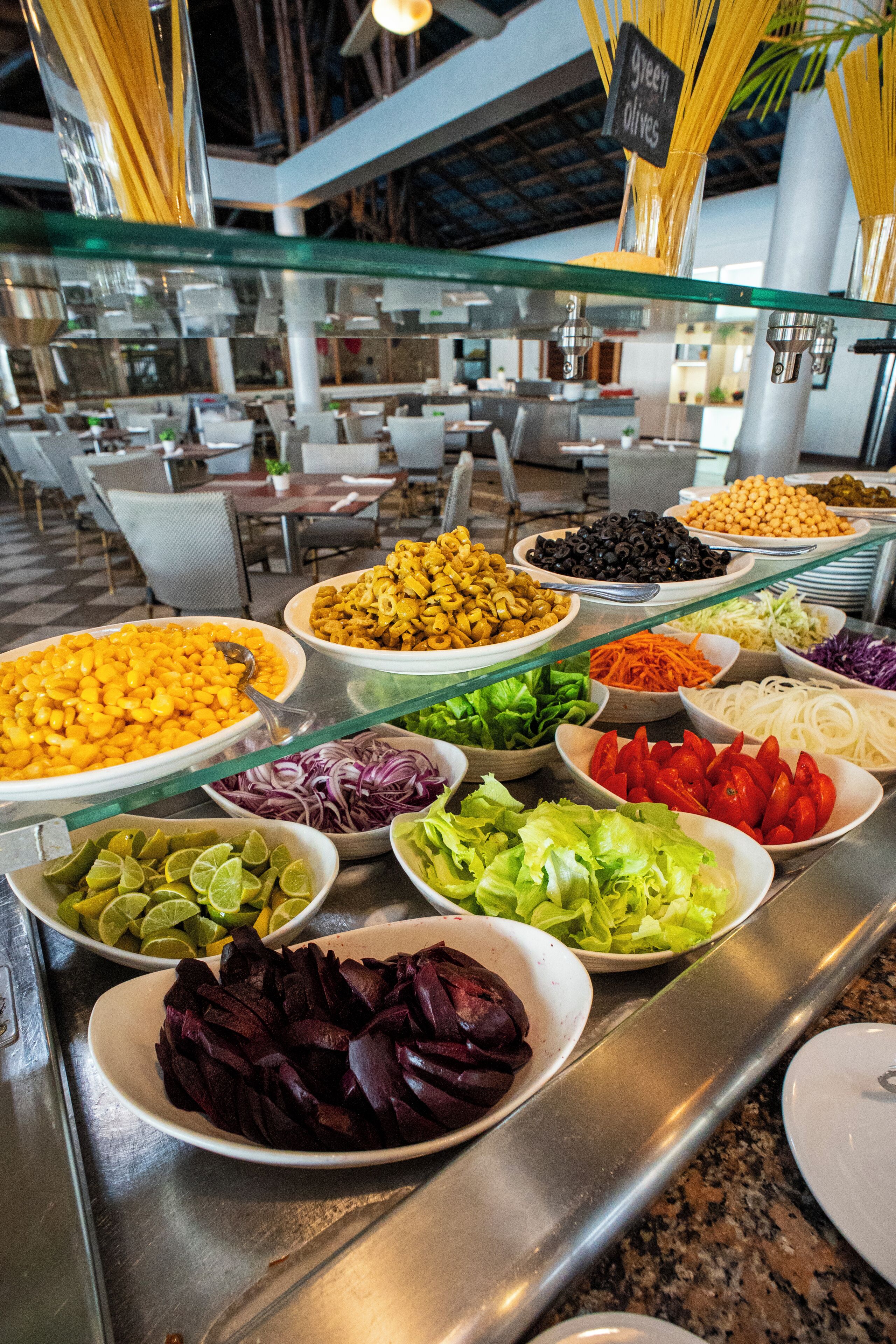 Buffet com diversos alimentos e uma vitrine de vidro.