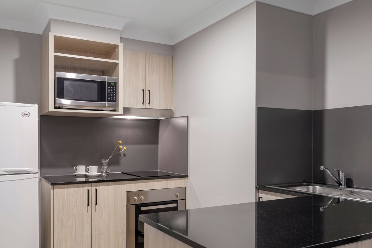 A modern kitchen with a built-in microwave, oven, and sink.