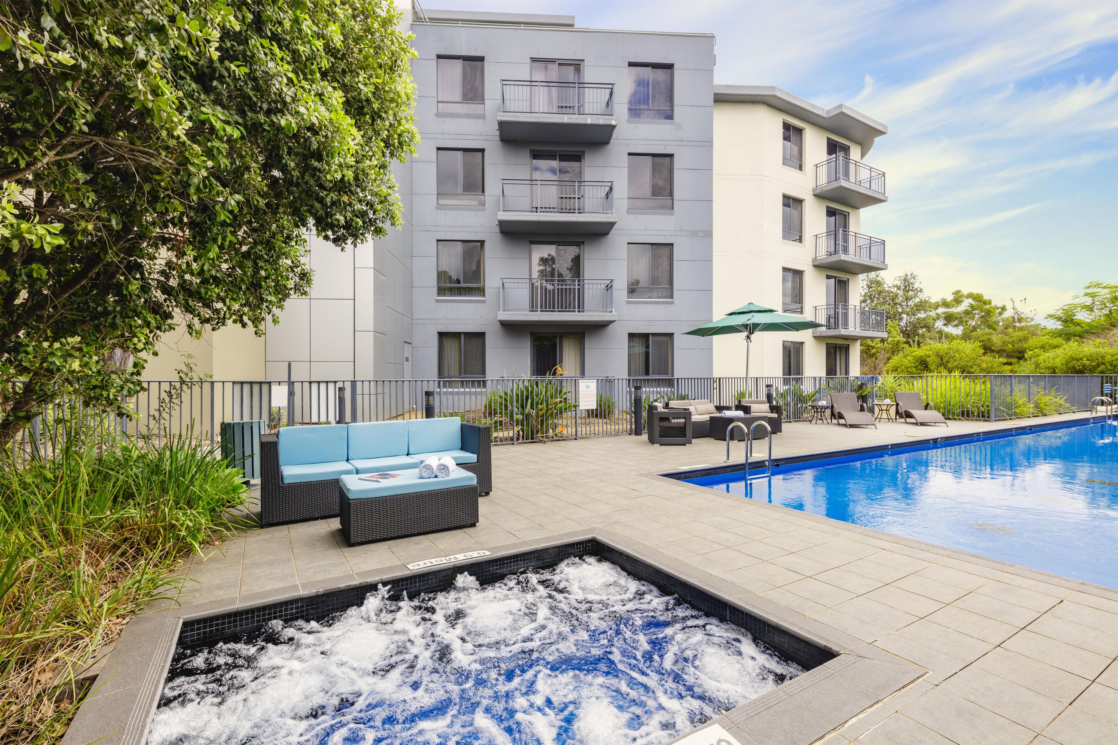 A modern building with a pool, outdoor seating, and a hot tub.