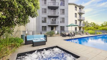 A modern building with a pool, outdoor seating, and a hot tub.
