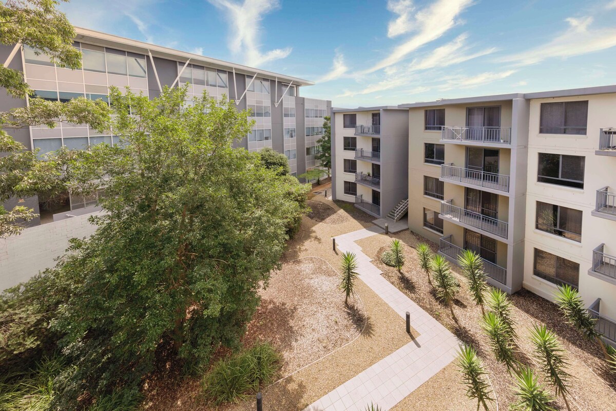 A modern multi-story building with balconies and a courtyard.