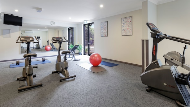 Un gimnasio con equipo de ejercicio, un espejo grande y una puerta que da al exterior.