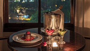 Una mesa con un postre, un cubo para champán y copas, frente a una ventana con vista a la ciudad.