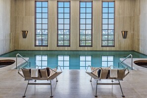 Zona de piscina con dos sillones de descanso y amplios ventanales con vistas a la ciudad.
