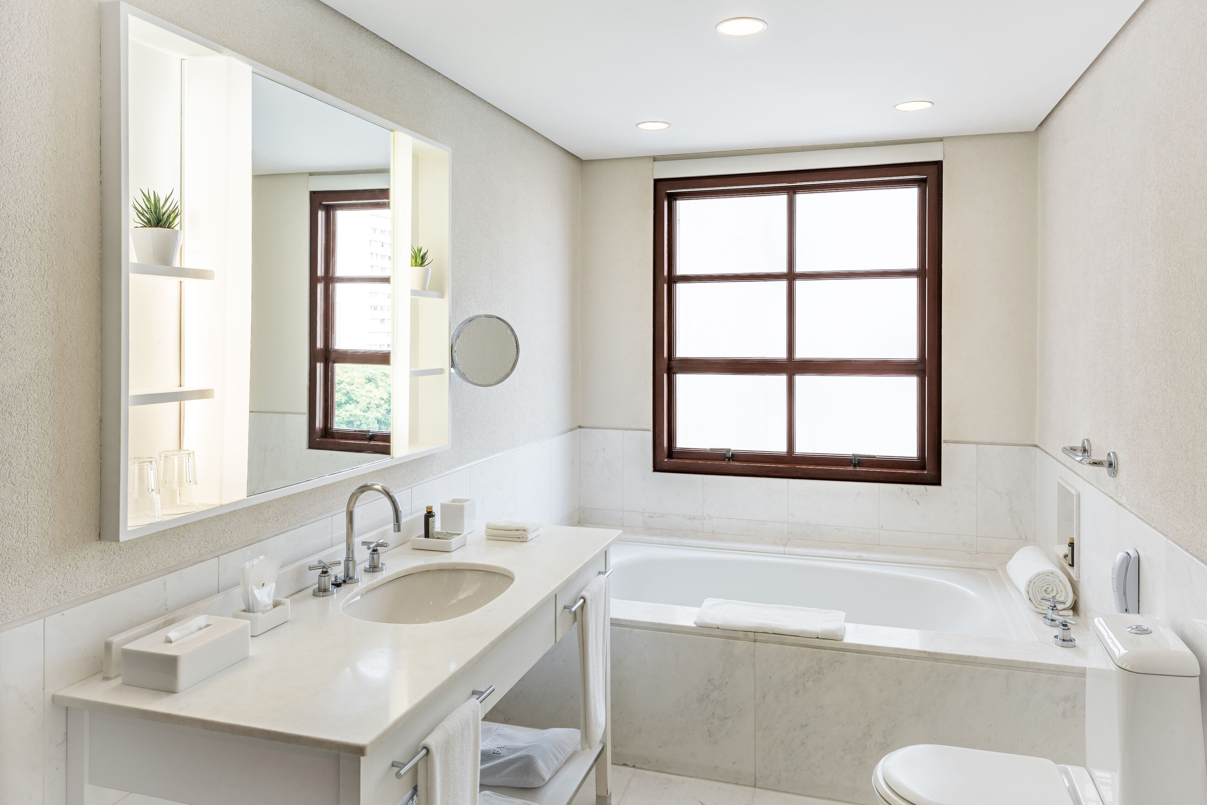 Un baño moderno con un espejo grande, dos lavamanos, una bañera y un inodoro.