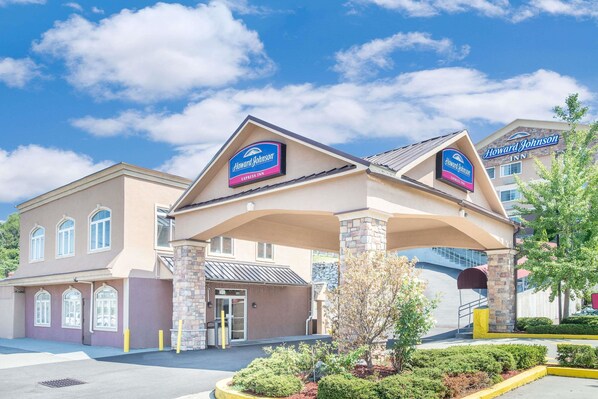 A Howard Johnson Express Inn with a two-story building, a covered entrance, and a landscaped area with bushes and a tree.