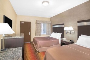 A hotel room with two beds, a desk, a telephone, and a window with curtains.