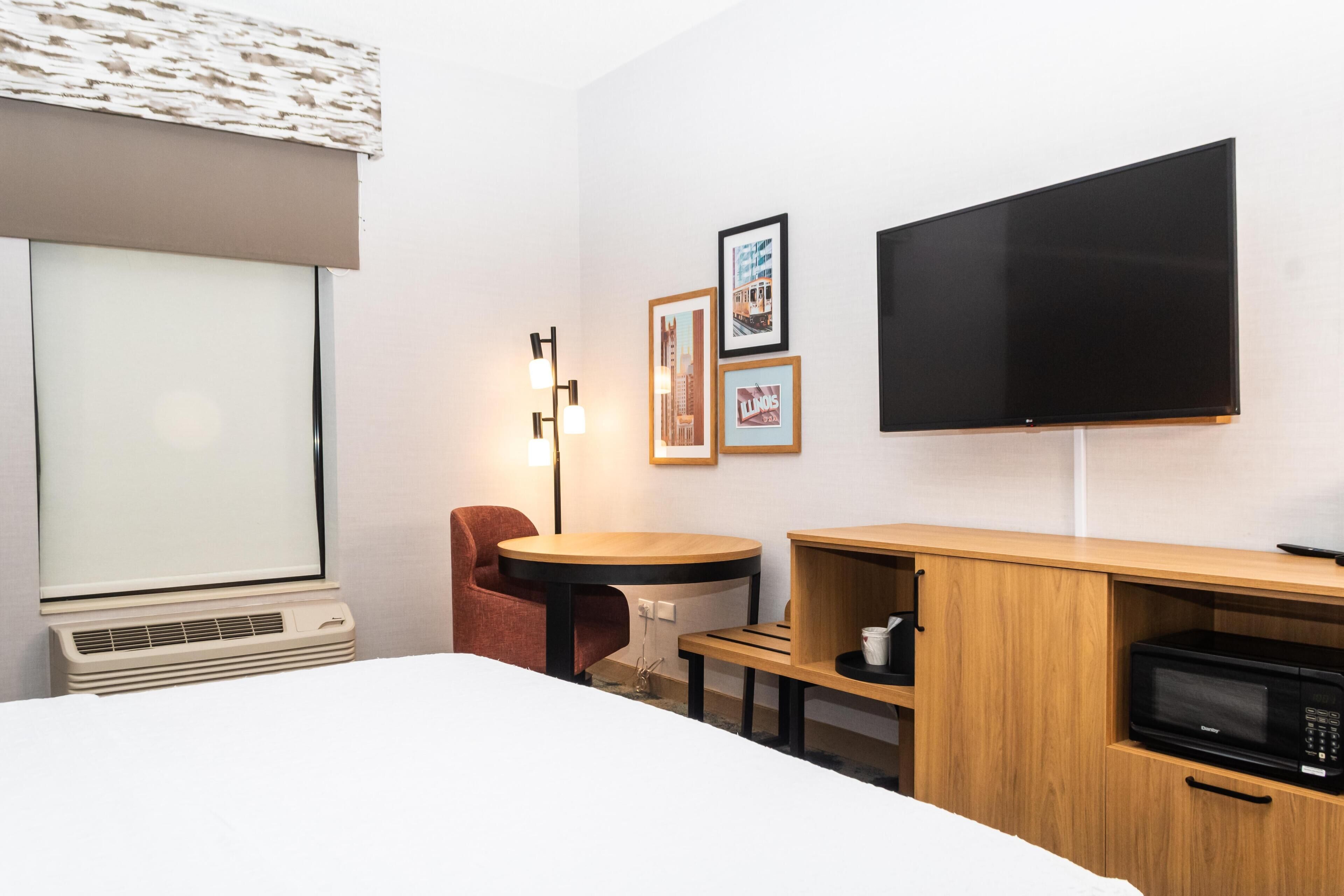 Habitación de hotel con cama, escritorio, silla, televisión de pantalla plana y microondas.