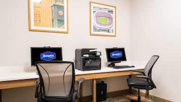 A hotel office with two monitors, a printer, and two office chairs.