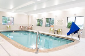 Una piscina con un puesto de salvavidas, sillas de descanso y un letrero de advertencia.