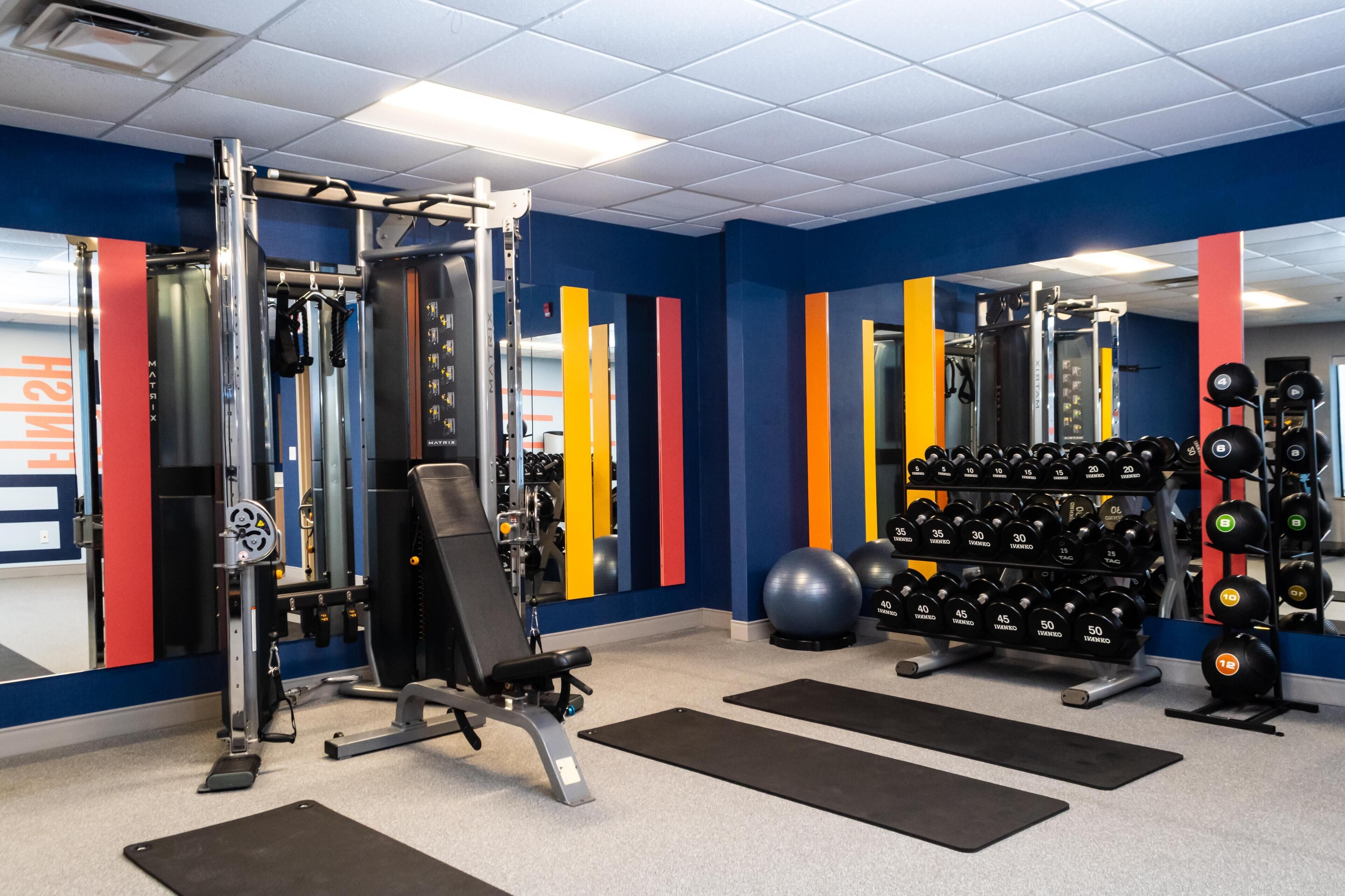 A gym with weightlifting equipment, exercise balls, and a mirror.