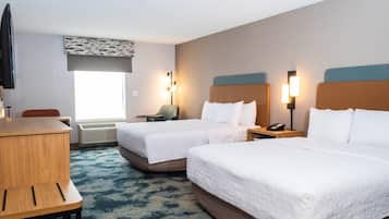 A hotel room with two beds, a desk, a chair, a TV, and a window with blinds.