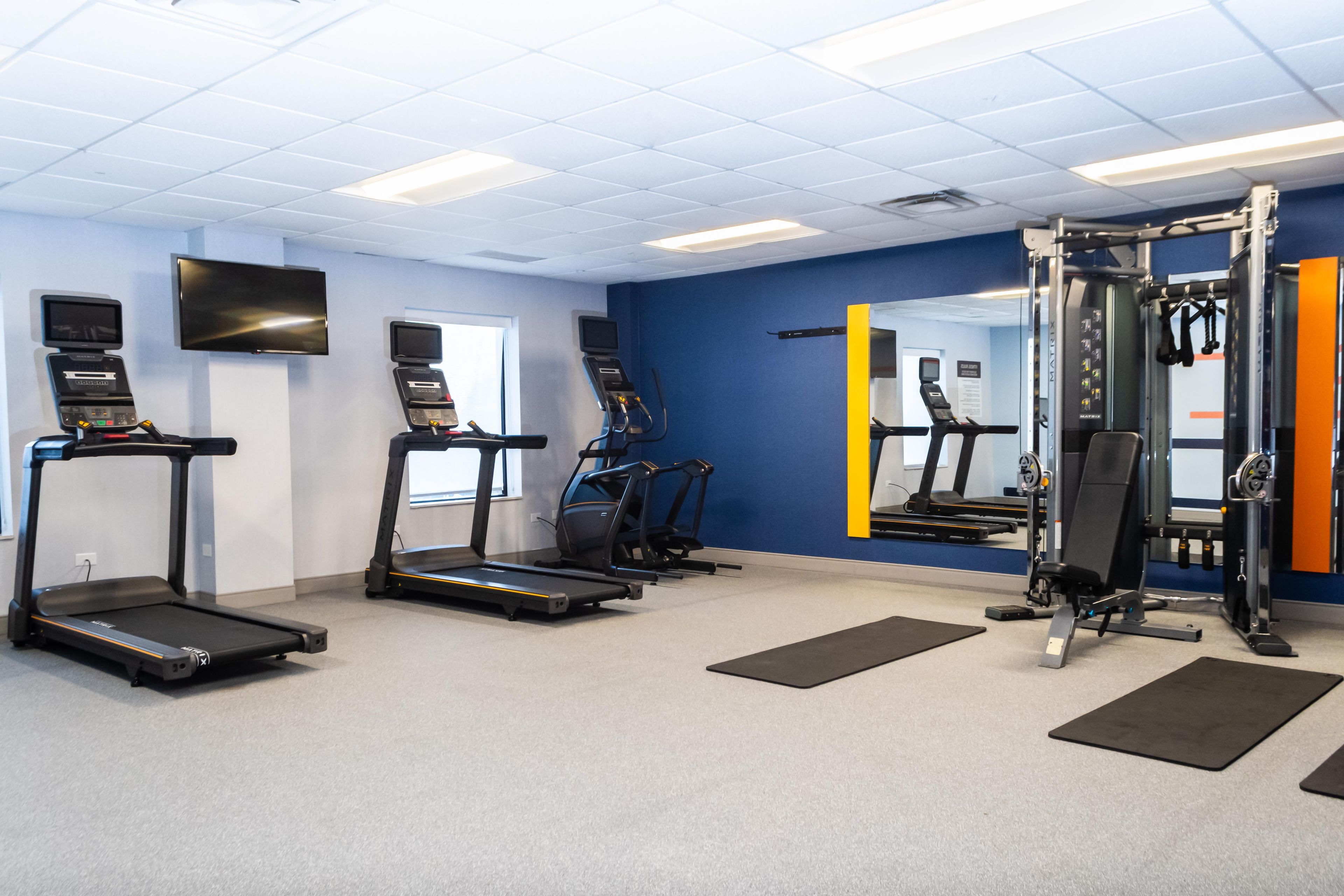 A gym with treadmills, a weight machine, and a mirror.