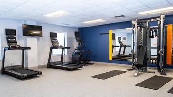 A gym with treadmills, a weight machine, and a mirror.