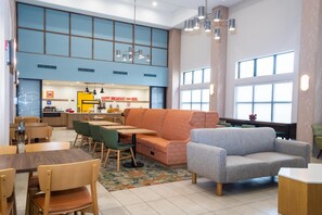 A modern interior with seating, tables, and a kitchen area. - Hampton Inn & Suites Addison (Addison)