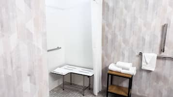 A modern bathroom with a shower, a towel rack, and a small table.