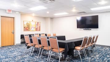 A conference room with a large table, chairs, a flat-screen TV, and an exit sign.