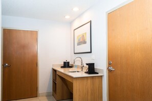 A small bathroom with a wooden vanity, a sink, a mirror, and a framed picture on the wall. - Hampton Inn & Suites Addison (Addison)