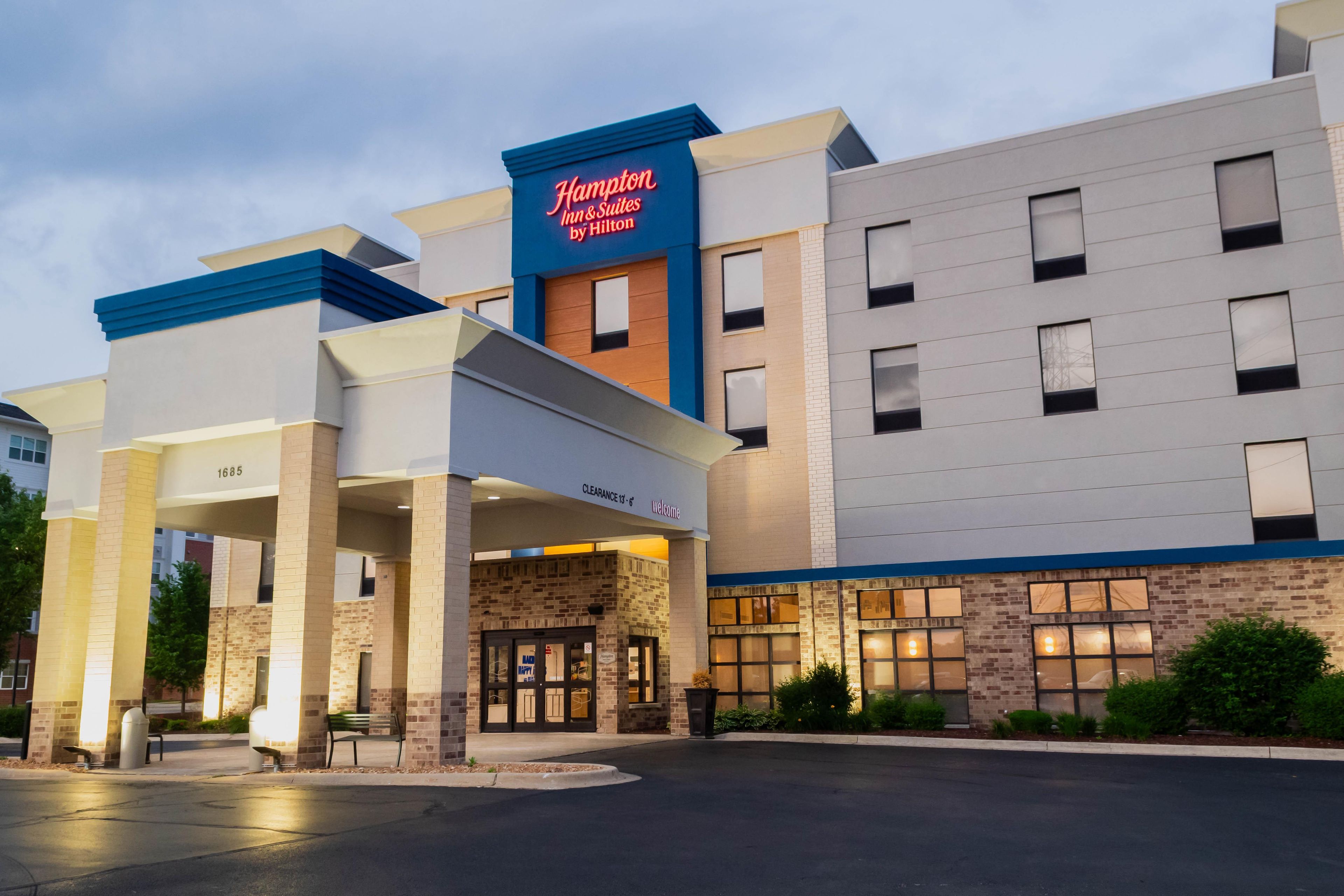 Hotel Hampton Inn & Suites by Hilton con fachada moderna, entrada despejada y estacionamiento.