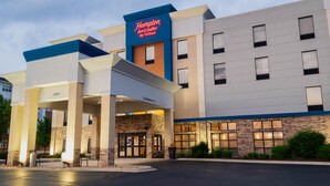 A Hampton Inn & Suites by Hilton hotel with a modern facade, a clear entrance, and a parking lot.