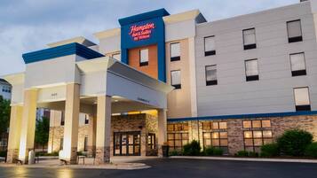 Hotel Hampton Inn & Suites by Hilton con fachada moderna, entrada despejada y estacionamiento.