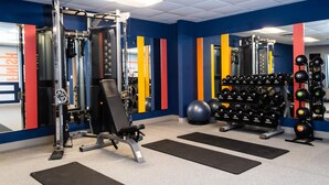 A gym with weightlifting equipment, exercise balls, and a mirror.