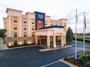 Un hotel Hampton Inn & Suites by Hilton con fachada de ladrillo, entrada cubierta y estacionamiento.