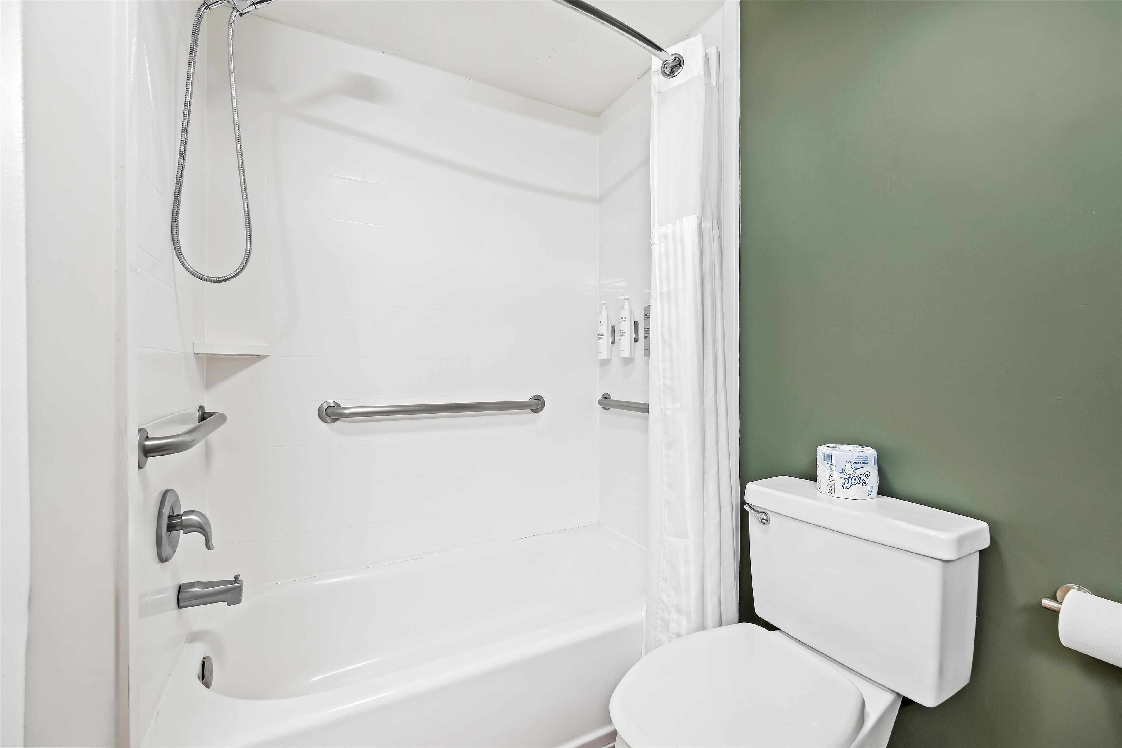 Une salle de bain avec une baignoire, des toilettes et un rideau de douche.