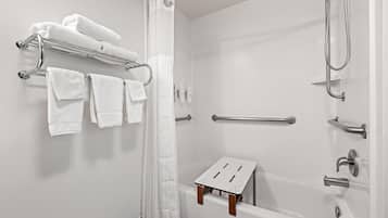 A modern bathroom with a bathtub, shower, and a small wooden stool.