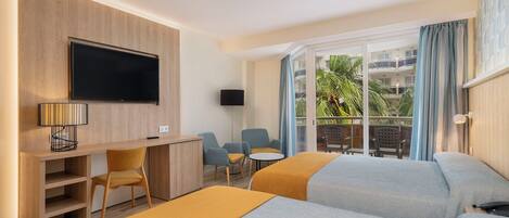 Habitación de hotel con dos camas, un escritorio con televisor, una silla, una mesita y un balcón con vistas al exterior.