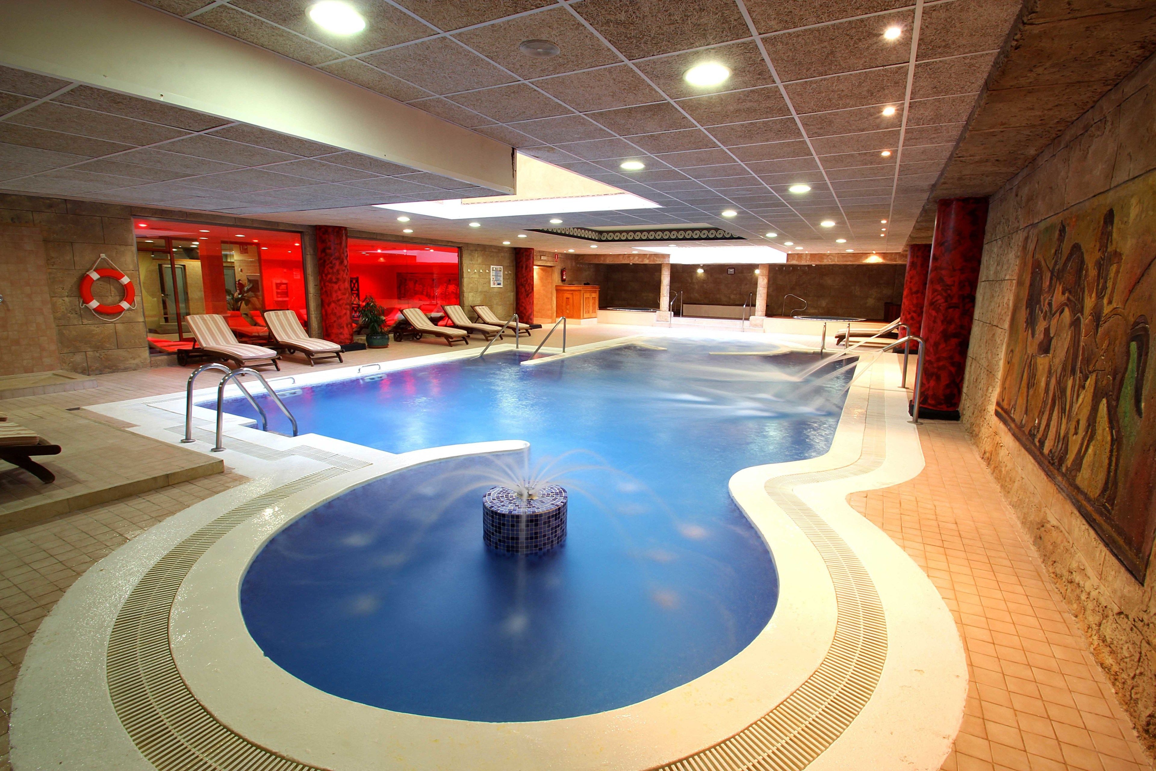 Una piscina interior con sillones de descanso y una fuente.