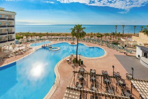Un complexe hôtelier doté d’une grande piscine, de chaises longues et offrant une vue sur l’océan.