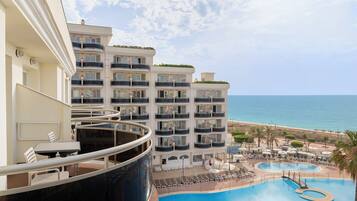 A hotel with multiple balconies overlooking a pool and beach.