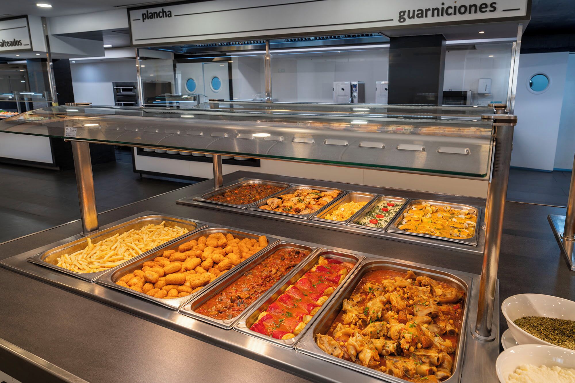 Un buffet con diverse opzioni tra cui patatine fritte, bocconcini di pollo e vari tipi di sformati.