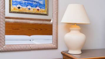A hotel room with a wooden headboard, a bedside lamp, and a framed painting on the wall.