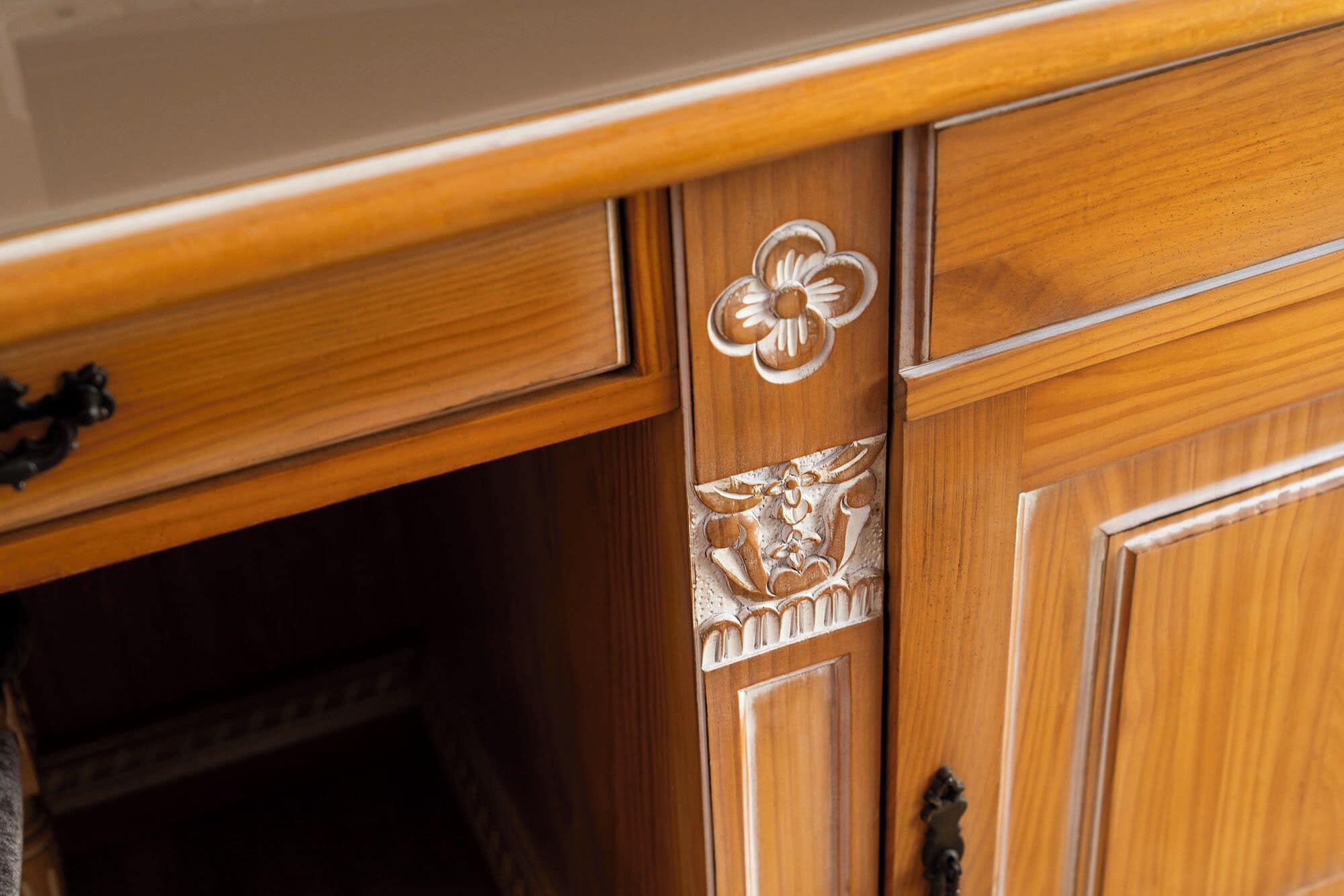 A wooden cabinet with intricate floral carvings and a brass handle.